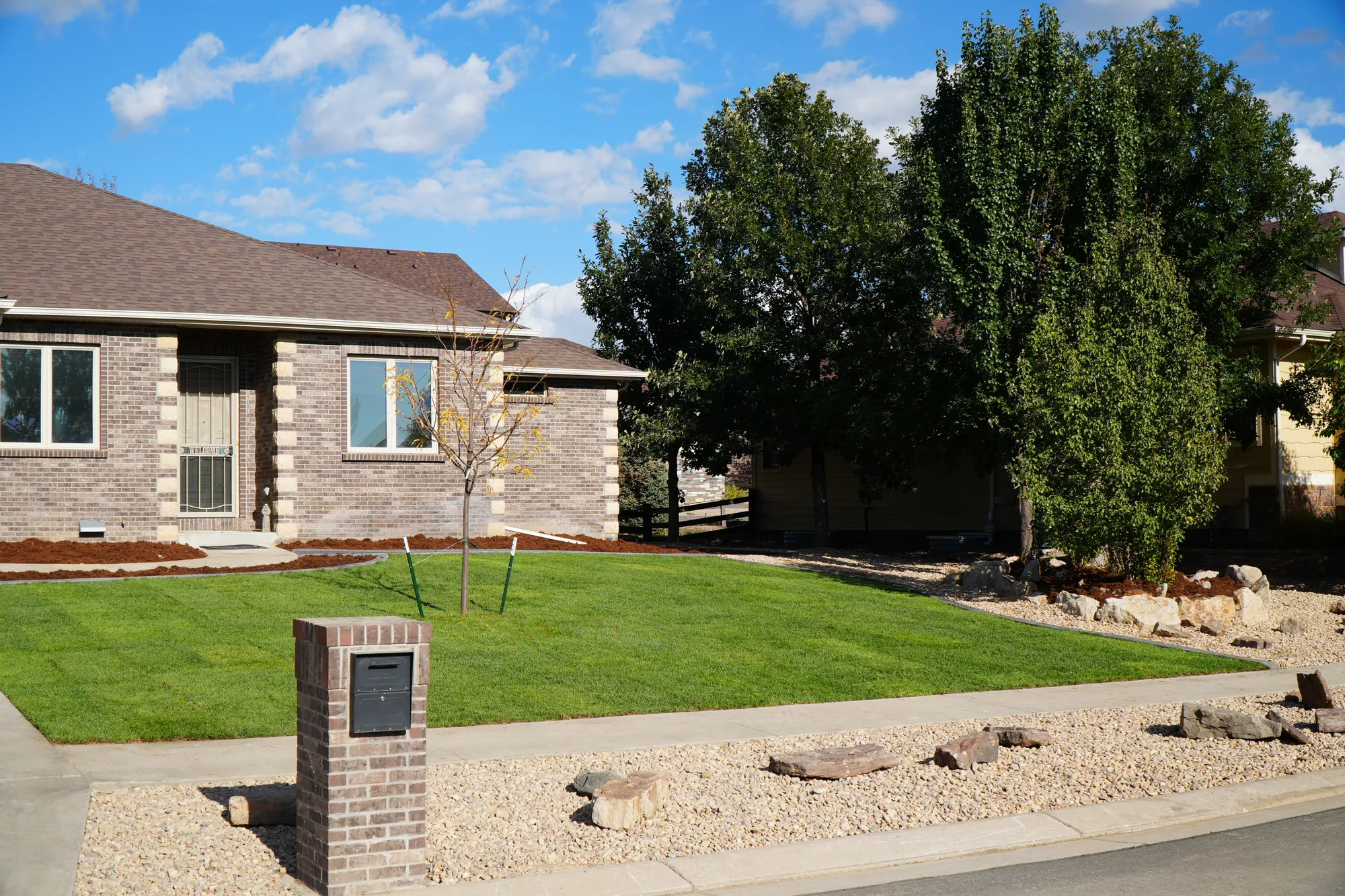 Front yard landscaping with new sod, rock border and boulders by Calaway Sprinkler